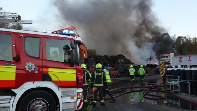 A fire engine and firefighters deal with a blaze