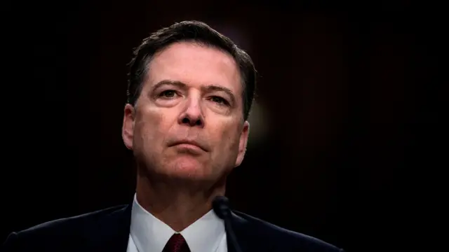 James Comey is photographed against a dark background