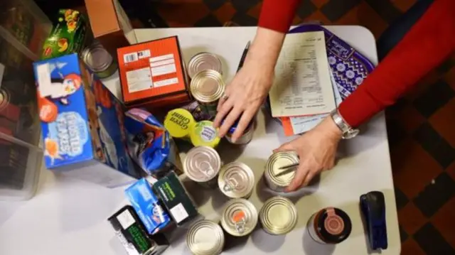 A woman picks up a selection of tins