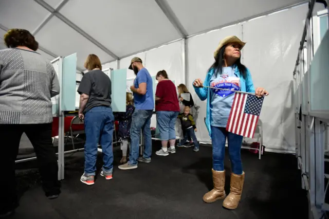 An election worker looks on as voters cast their ballots.