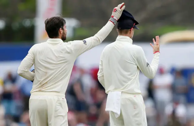 England's Ben Foakes (L) picks up his cap from captain Joe Root's head