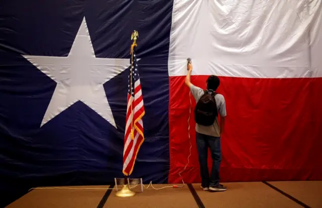 A worker irons the Texas flag