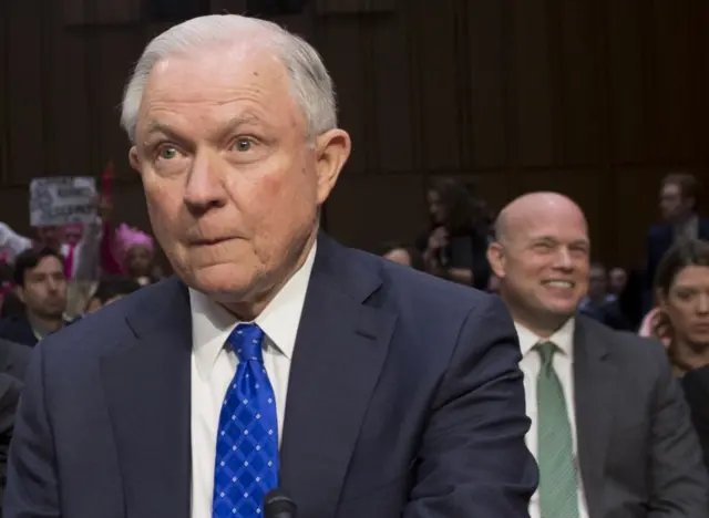 Jeff Sessions, with Matthew Whitaker pictured seated behind him