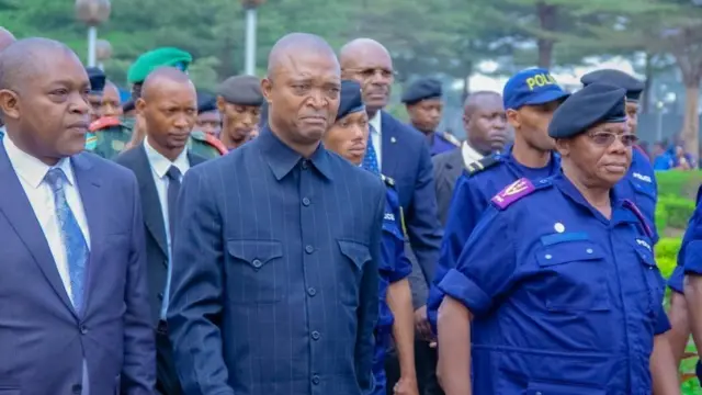 Emmanuel Ramazani Shadary walks among a delegation and police officers