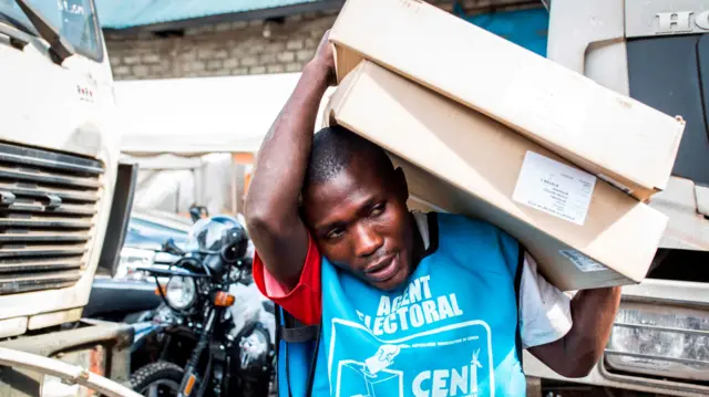 A electoral worker carrying boxes in DR Congo