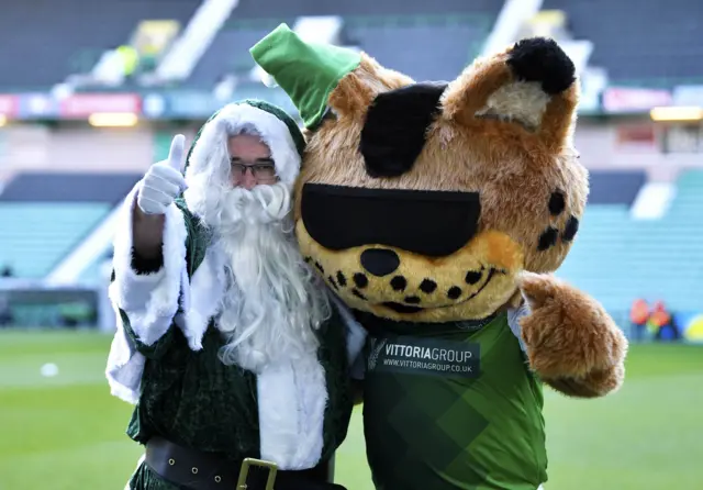 A green-themed Santa and the Hibernian mascot enjoy a festive embrace