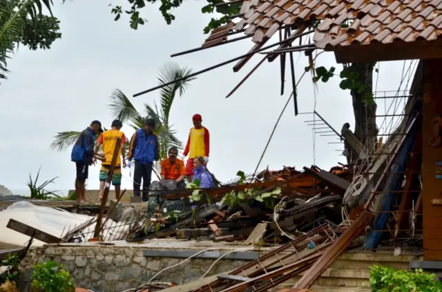 Officials look through the wreckage of damaged buildings in Carita