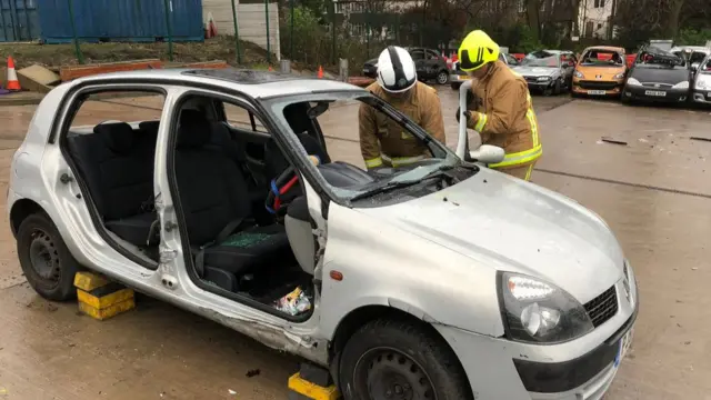 Firefighters next to a smashed up car