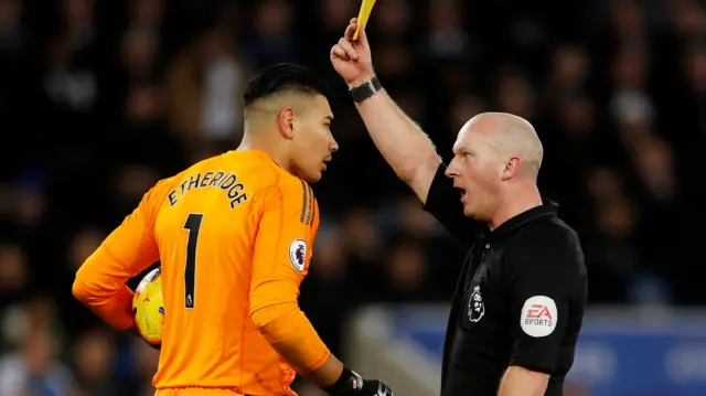 Referee Simon Hooper shows Cardiff's Neil Etheridge a yellow card