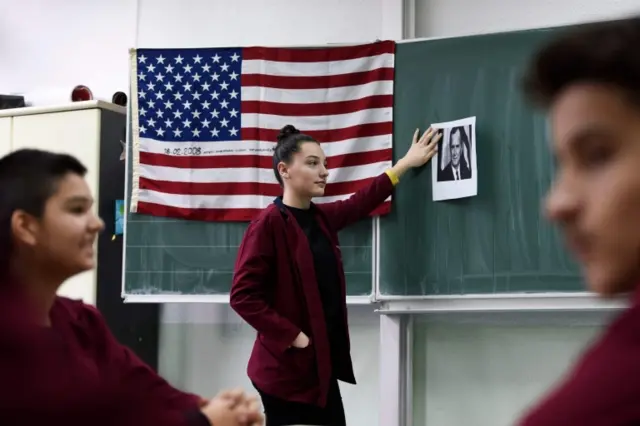 Student holds image of Bush on chalkboard