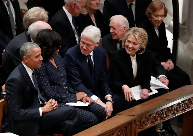 Bill and Hillary Clinton look over at Barack and Michelle Obama, with former President Jimmy Carter and first lady Rosalynn seated behind them