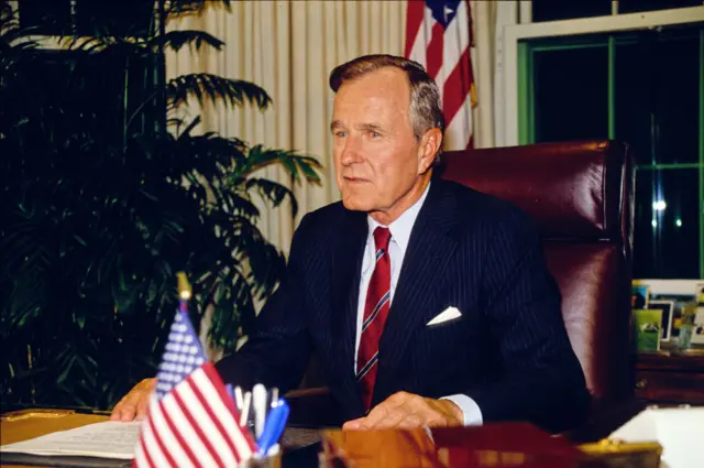 US President George HW Bush sits behind his desk in the White House's Oval Office, Washington DC, October 2, 1990. (Photo by Howard L. Sachs/CNP/Getty Images)