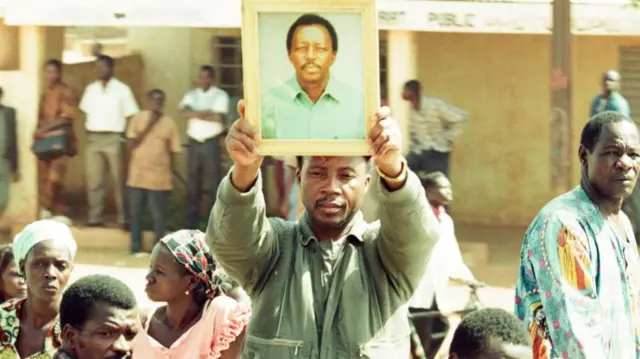 A relative holding up a photo of Norbert Zongo at his funeral in 1998