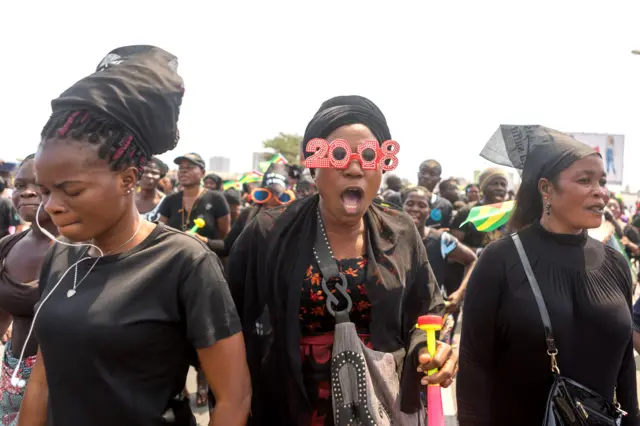 A Togolese woman dressed in black and wearing a pair of masquerade sunglasses, takes to the streets of the capital Lome during a protest rally against Togo's president on January 20, 2018.