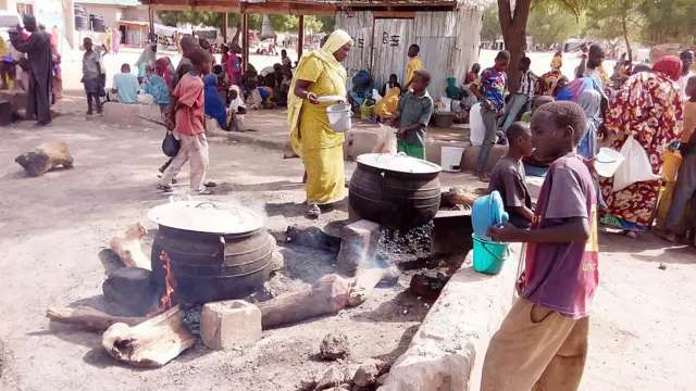 A woman prepares food for lunch in an open-air kitchen for people displaced by Boko Haram violence on May 19, 2016 in the Dalori Internally Displaced People's (IDP) Camp, near Maiduguri, northeast Nigeria