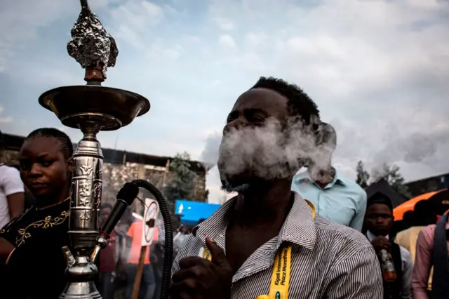 A Congolese festival-goer smokes from a hookah during the Amani Festival on February 10, 2018 in Goma. The Amami Festival runs from Febraury 9 to 11, promoting peace and culture in eastern Democratic Republic of Congo and Great Lakes region.