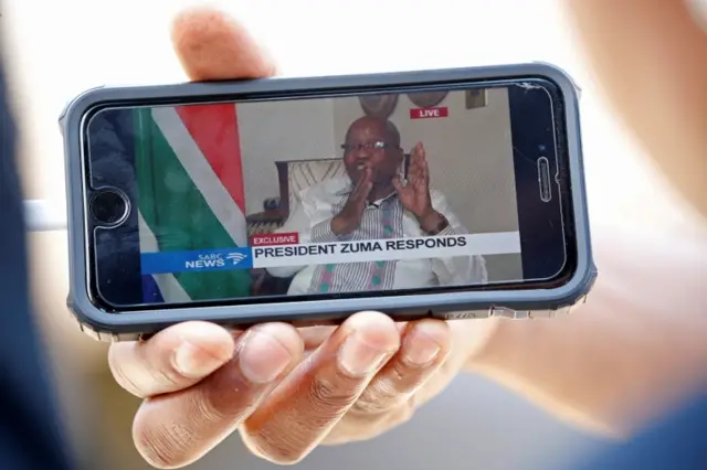 Members of the media watch South Africa President Jacob Zuma's statement on a mobile device in Pretoria, South Africa February 14, 2018.