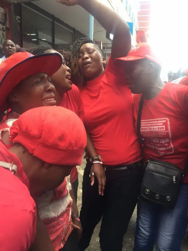 MDC supporters stand together crying and mourning the death of their leader Morgan Tsvangirai