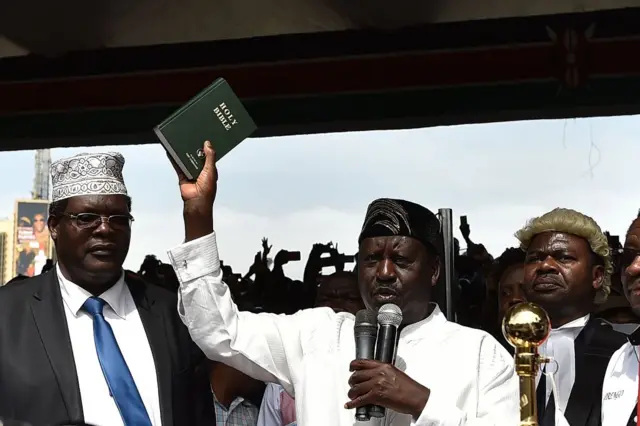 Raila Odinga hold a copy of the Bible as he is "sworn in" as "people's presiednt" at a mock ceremoney