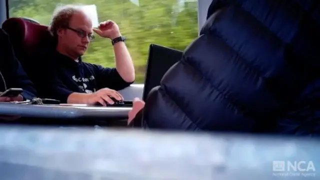 Falder looking at a laptop computer on board a train