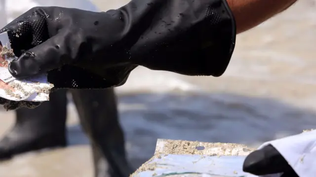 A Libyan coastguard shows pictures and documents found on the body of a migrant that had washed ashore on a beach on August 28, 2015 in the port town of Zuwara, about 160 kms West of Tripoli, after two boats carrying hundreds of migrants and refugees sank off the coast of the town