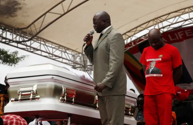 A pastor prays next to Morgan Tsvangirai's coffin