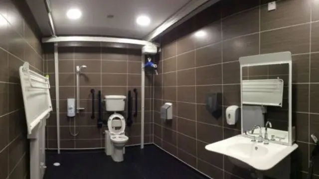 A Changing Places toilet with a hoist and adjustable adult sized changing bench.