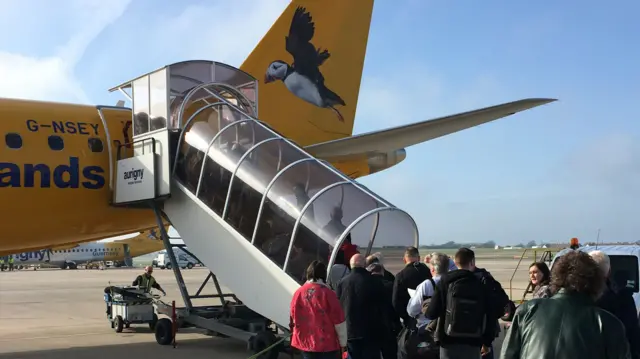 Aurigny passengers queue to get on to a flight