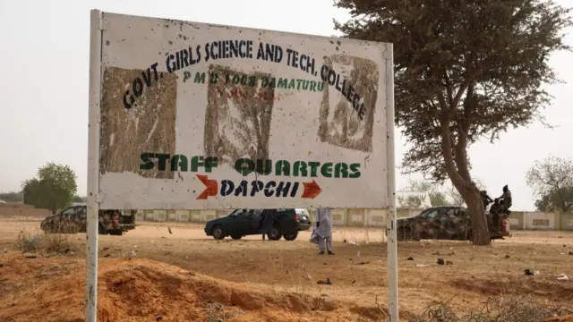 Soldiers (R) drive past a signpost leading to the Government Girls Science and Technical College staff quarters in Dapchi, Nigeria, on February 22, 2018