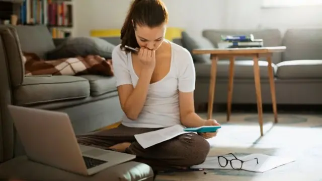 Woman looking worried with calculator in hand