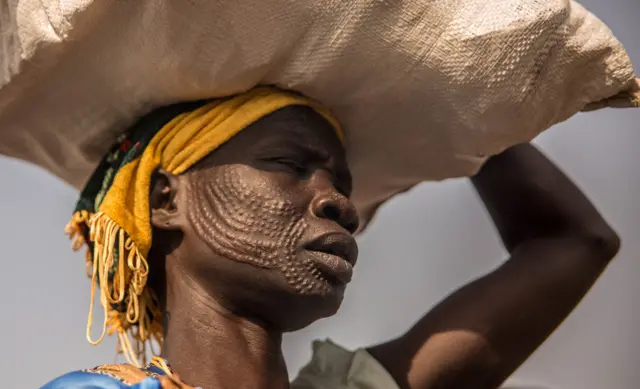 A woman from Nuer ethnic group carries her food after a monthly food distribution at the Protection of Civilian site (PoC) in Bentiu, South Sudan, on February 13, 2018.