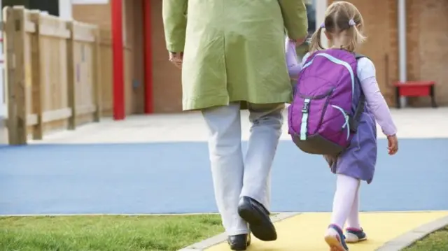 Adult walking child to nursery