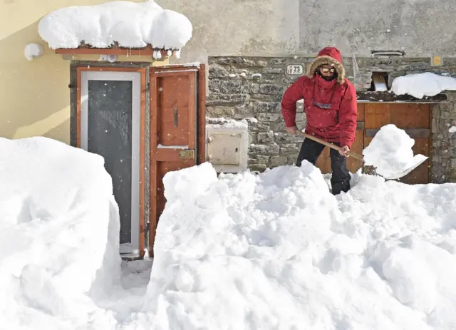 A person shovels snow after a heavy snowfall in Casaglia, Mugello, Florence"s province, Italy