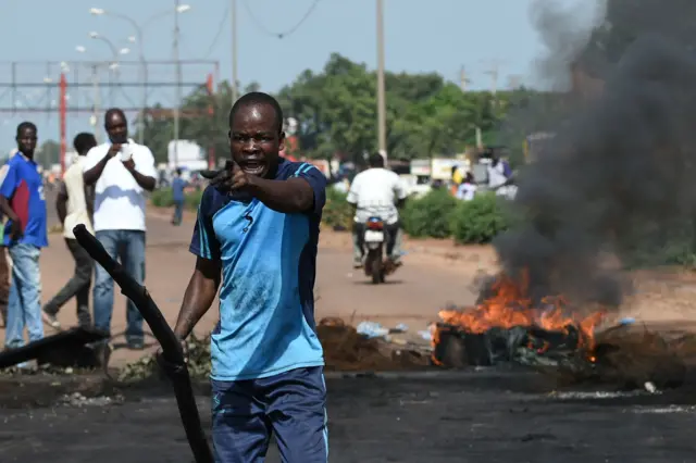 A man gestures next to a tyre set on fire during a protest against a regional proposal to end the crisis, five days after a military coup, in the Tampouy neighborhood of Ouagadougou, on September 21, 2015.