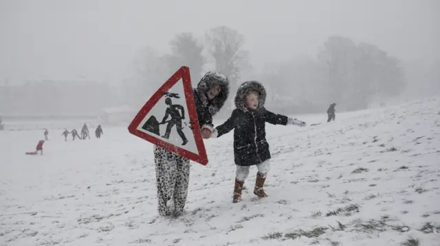 A sign is used as a sledge in the snow in Jacksons Field in Rochester