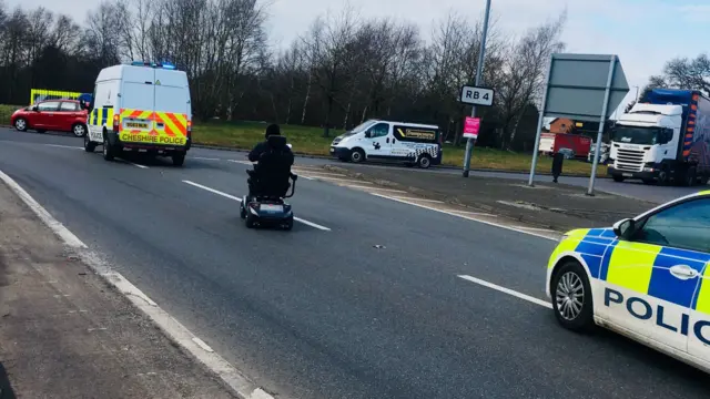 Police escort to safely get a man in a mobility scooter off a busy A-road.