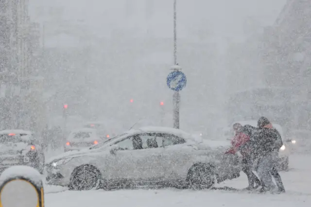 People push car in snow