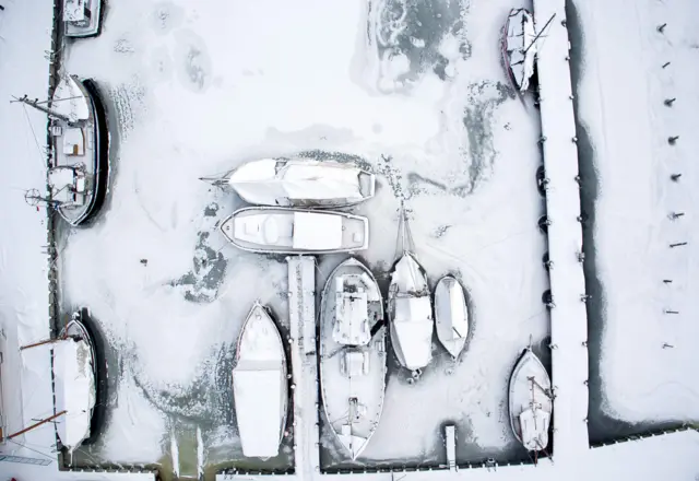 Picture taken with a drone shows snow-covered sailing ships mooring at the boatyard harbour of Kirchdorf on the Baltic Sea island of Poel, northeastern Germany