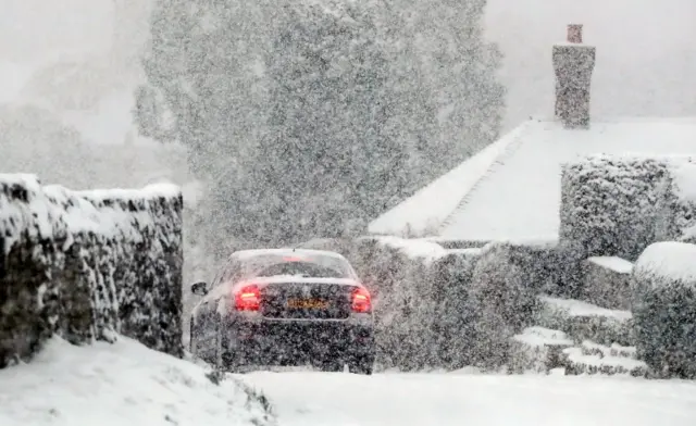 A car travels through snow in Ashford, Kent,