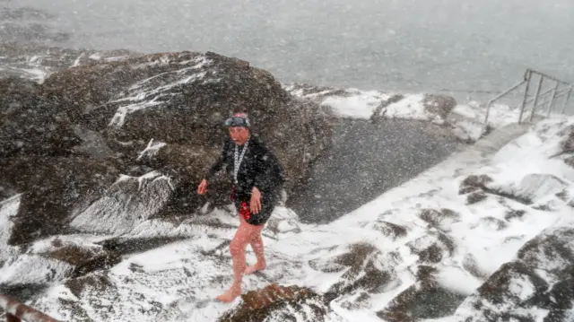 Members of the Battery Belles and Buoys, a wild sea swimming group that swim every day in the sea at from the Battery Rocks in Penzance take a dip in the sea as heavy snow arrives