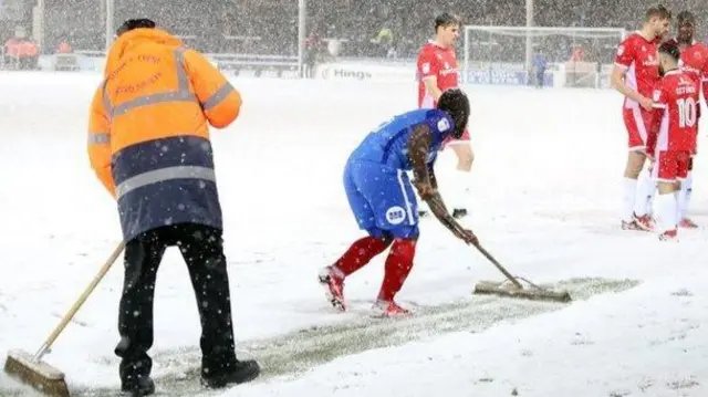 Players clearing pitch of snow