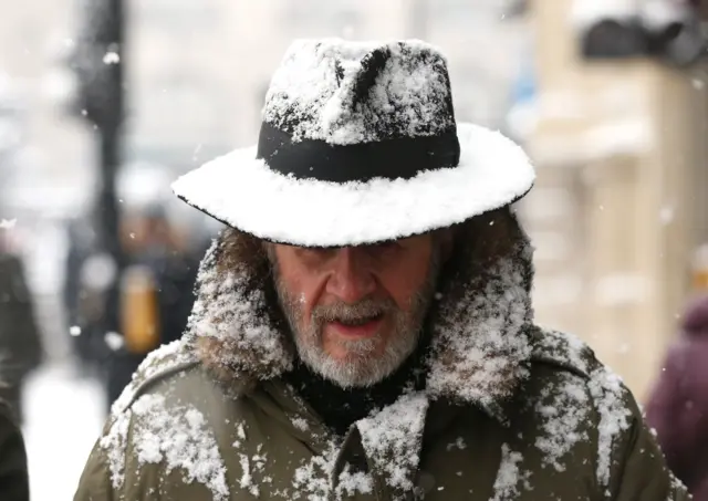 Man walking in the snow in Coventry Street, London