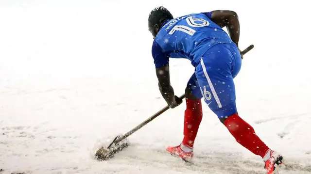 One of Peterborough's players sweeping at the snow