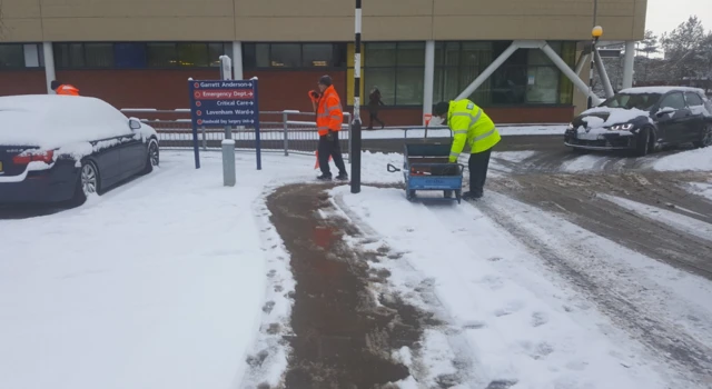 People work to clear ice and snow from paths outside Ipswich Hospital