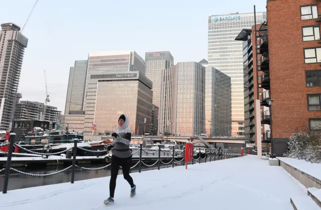 A woman jogging in the snow in Canary Wharf, London