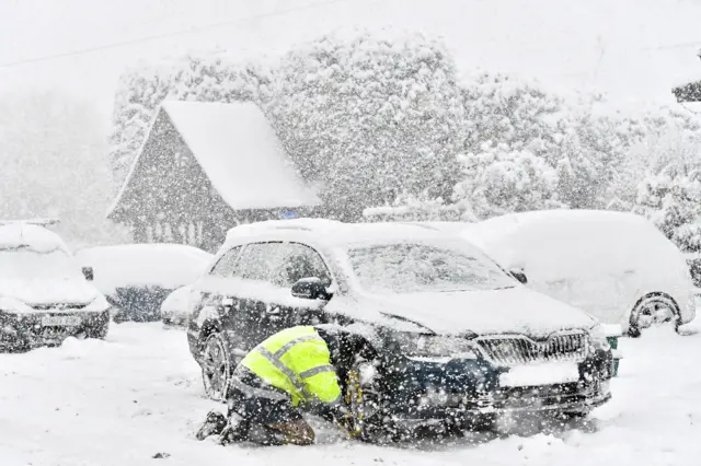 A mechanic replaces a tyre in the snow