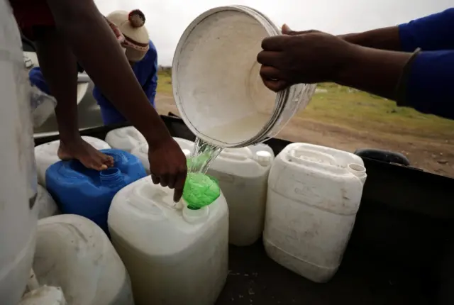 Residents fill up a containers with water from a polluted river near Cape Town. Photo: 2 February 2018