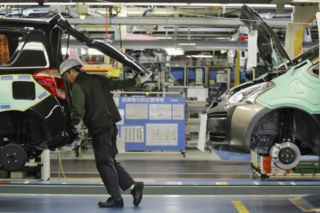 A worker inspects a Toyota car at a factory in Japan