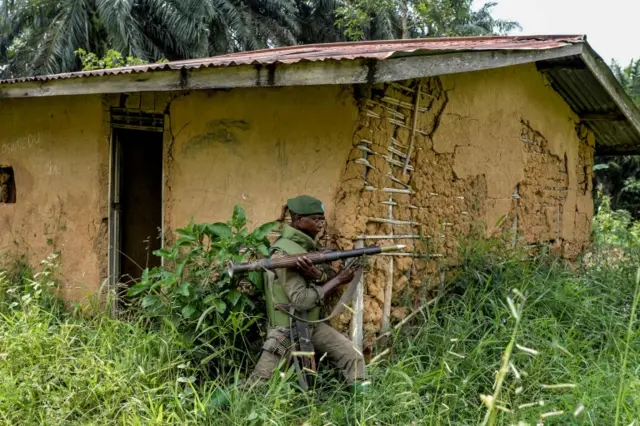 A soldier of the FARDC (Armed Forces of the Democratic Republic of the Congo) takes cover during exchanges of fire with members of the ADF (Allied Democratic Forces) in Opira, North Kivu, on January 25, 2018. /