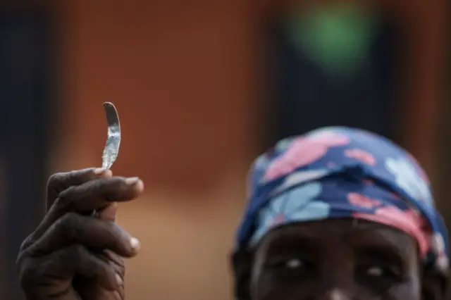 A former female genital mutilation (FGM) cutter shows a homemade tool from a nail used for FGM